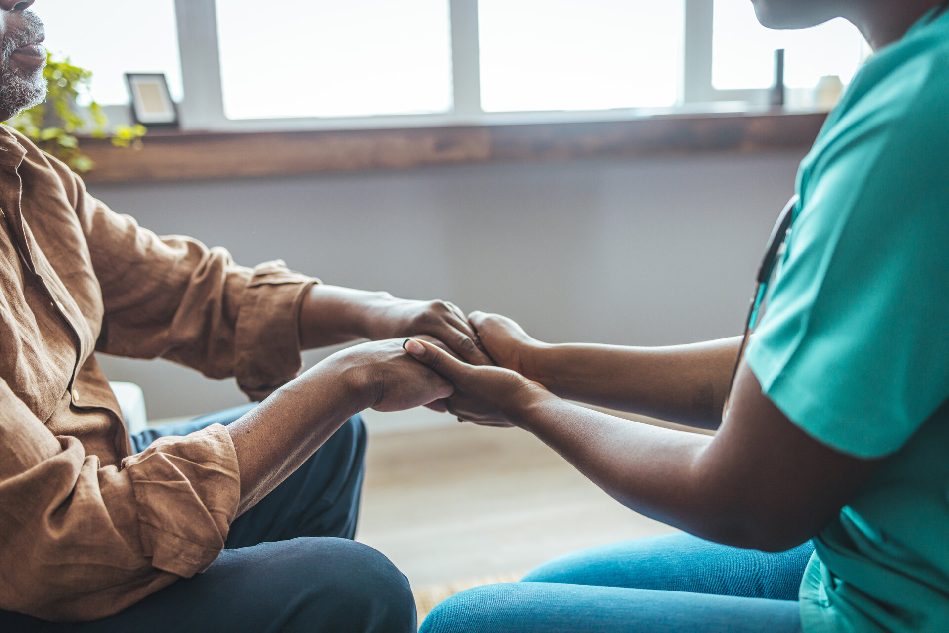 Caregiver providing professional care holding hands with elderly patient
