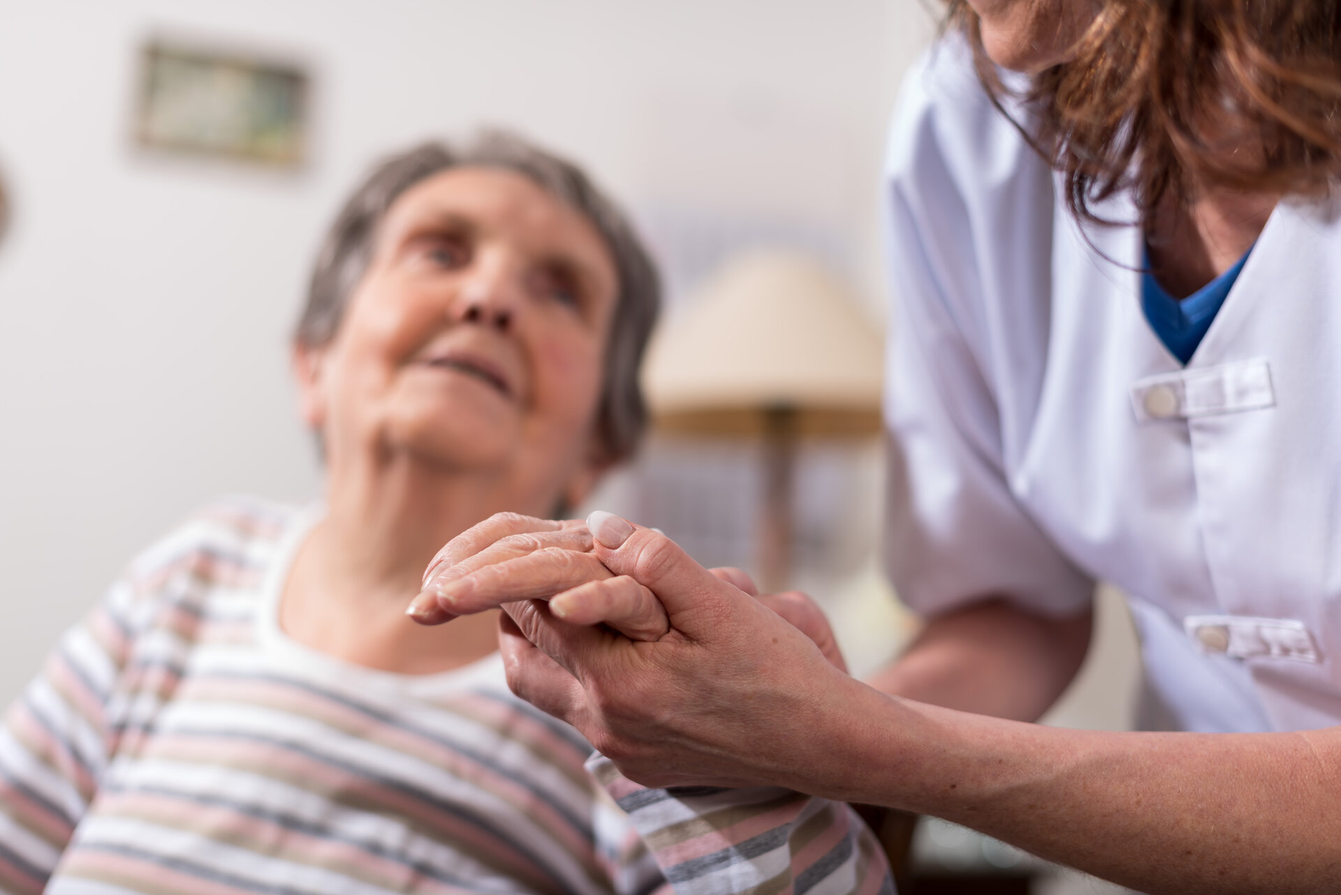 Caregiver holding hands with elderly patient